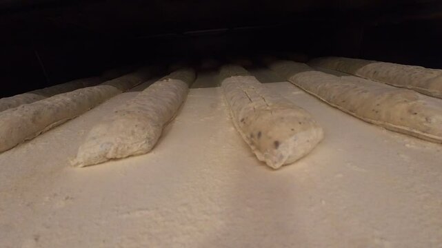 Insertion des baguettes de pains dans le four du boulanger en vue pour la cuisson, plan en immersion sur le plan de travail, la cam&eacute;ra rentre dans le four