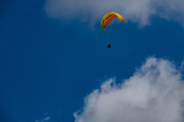 Paraglider flight against a blue sky with clouds. Beskidy Mountains, Poland