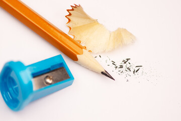 A sharpener and a gray graphite pencil on a white background, close up. Tools and accessories for drawing.