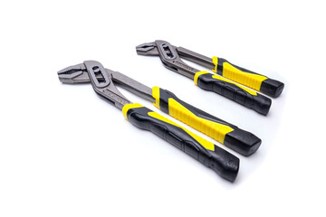 Two slip joint pliers with yellow and black handles lying on white background