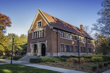 Historic brick building with elegant architecture surrounded by autumn foliage in a serene outdoor setting during early evening light