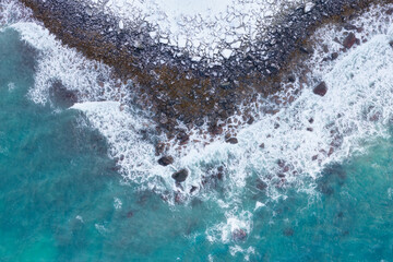Coast with waves as a background from top view. Blue water background from drone. Natural winter landscape from air. Landscape from drone. Photo for postcards, backgrounds, wallpapers.