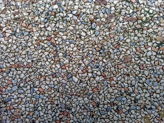Textured surface of colorful pebbles in a garden setting on a sunny day
