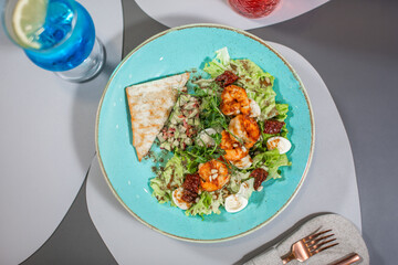 A plate of food with shrimp and salad on a blue plate