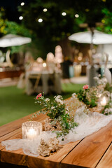 Outdoor table setting with floral centerpiece and candles, creating a romantic ambiance for an evening event.
