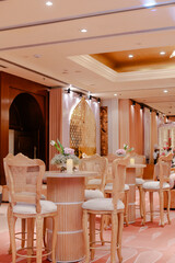 Elegant event space with light wood bar stools and tables, adorned with simple floral arrangements.  Perfect for a sophisticated gathering.