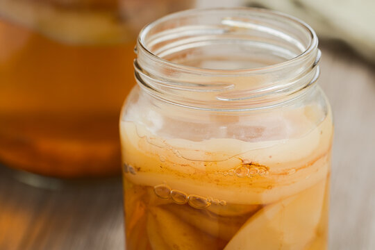 Homemade black tea kombucha or tea mushroom in glass jar with lots of scoby, a healthy fermented probiotic drink (Selective Focus, Focus on the front of the top scoby)