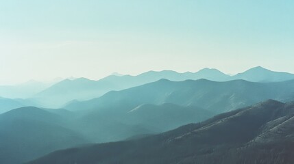 Fototapeta premium Layers of mountains fade into the horizon under a soft pastel sky, capturing an ethereal and tranquil landscape.