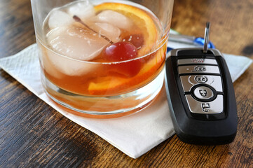 Drink and Drive, drunk driver concept - mixed drink liquor cocktail with key fob for vehicle at bar