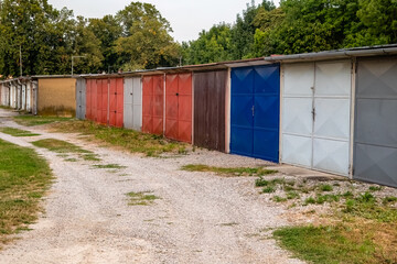 Old terraced garages with gravel driveway.