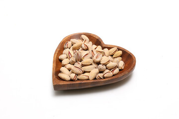 白背景の木製の皿にのせたピスタチオ