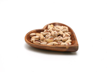 白背景の木製の皿にのせたピスタチオ