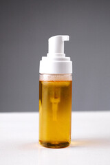 Clear liquid in pump bottle displayed on table against gray background showing product design and color