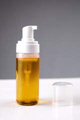 Bottled oil with pump dispenser placed on a clean surface near a clear cap