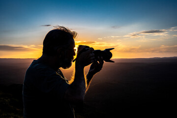 Fototapeta premium Backlit photographer focuses his camera on a sunset in Cuchi Corral, Córdoba Province, Argentina.