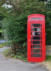 Red phone booth in Seaford with trees in the background. East Sussex, England, United Kingdom