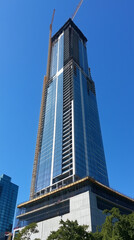 Fototapeta premium Modern high-rise building under construction with cranes