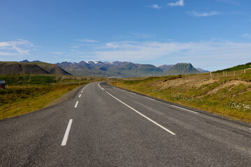 Empty highway through Icelandic mountain landscape. Road with white markings leading to distant...