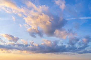 Pink clouds illuminated by evening sun on blue sky, dramatic sky.