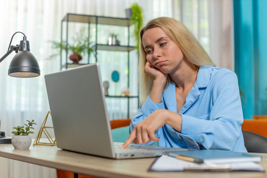Bored sleepy blond businesswoman worker working on laptop computer leaning on hand at home office desk. Exhausted tired Caucasian woman freelancer workaholic girl. Employment, occupation, workless.