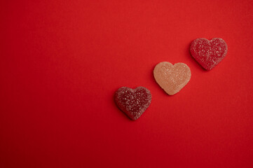 Heart-shaped gummy candies on a vibrant red background, symbolizing love and romance. Perfect for Valentine's Day themes, holiday promotions, greeting cards, and romantic celebrations