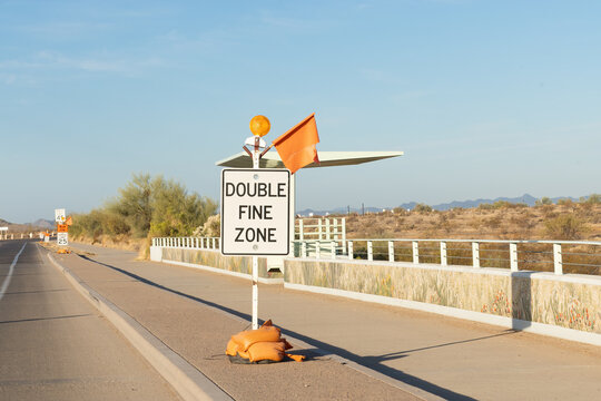 Road construction sign on the side of the road with speed limit signs in the morning or evening at the golden hour after sunrise or before sunset