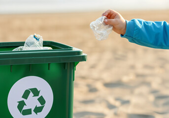 Child throwing a plastic bottle into a recycling bin on a beach, demonstrating responsible waste disposal and environmental awareness