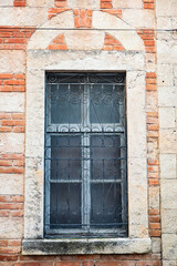 Vintage brick and stone window with ornate iron grille