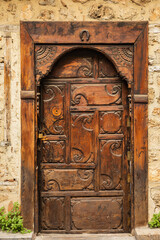 Ornate wooden door with carved patterns on rustic stone wall