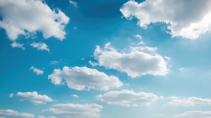 Fototapeta premium Fluffy white clouds drift across a vibrant blue sky, creating a serene and peaceful atmosphere. The sunlight enhances the tranquil setting, ideal for relaxation.