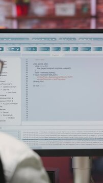 Vertical video Woman in home office looking at UI on PC screen, typing and executing programming code. Coding application UI used by IT developer writing and testing code in modern apartment, camera B