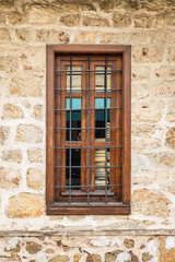 Rustic wooden window with bars on stone wall