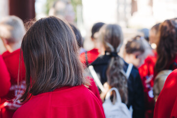 Group of school pupils and students on outdoor excursion tour in the city streets with guide, a docent with a tourist young visitors wearing red, school field trip, urban tour in the summer sunny day