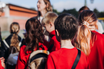 Group of school pupils and students on outdoor excursion tour in the city streets with guide, a...