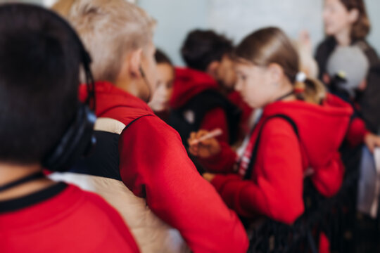 Group of kids children on excursion in a museum gallery, school pupils and students tour with guide, a docent with a tourists, young visitors wearing red, school field trip, art exhibition attendees