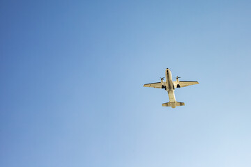 Small passenger airplane flying overhead against clear blue sky
