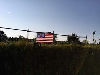 American Flag On A Fence In A Field