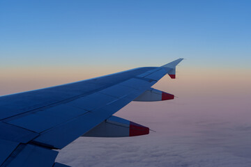 Obraz premium An airplane wing against a colorful sunrise sky.