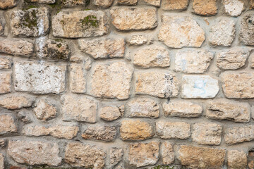 Textured stone wall with varied brick patterns and moss accents