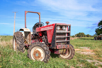 Obraz premium Red agricultural tractor outside on the farm in a rural area.