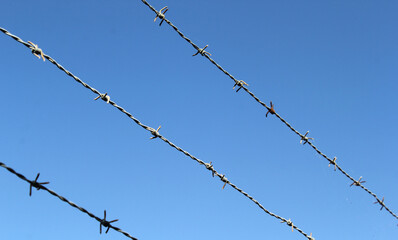 Barbed wire fence against a blue sky background