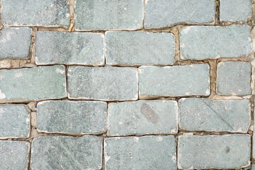 Close-up view of weathered stone pavement with rectangular slabs in earthy tones
