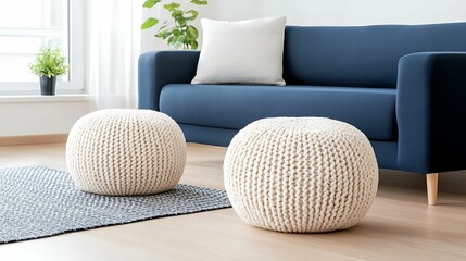 A cozy living room with a blue sofa, decorative pillows, and knitted poufs on a rug, surrounded by natural light and greenery.
