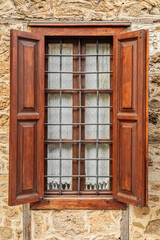Rustic wooden window with iron bars on stone wall