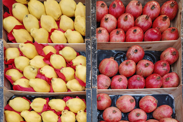 A vibrant display of fresh yellow quinces and red pomegranates neatly arranged in wooden crates at a market. 