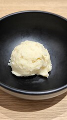 Mashed potatoes in a black cup on a wooden table