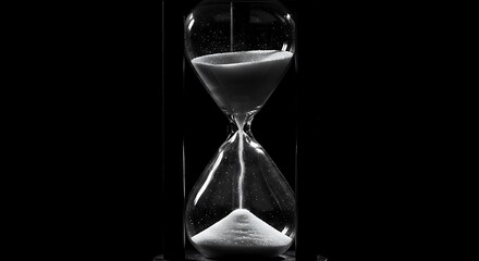 Vintage hourglass, flowing sand, monochrome time, passing moments in glass.