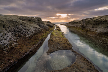 sunset over the rocks on the pacific ocean in California