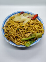 Fried noodles with soy sauce served with pickles, chili, vegetables and meat. Fried noodles with white background.