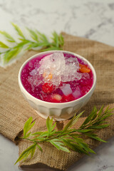 A white bowl of soup with yellow and green pieces of food in it